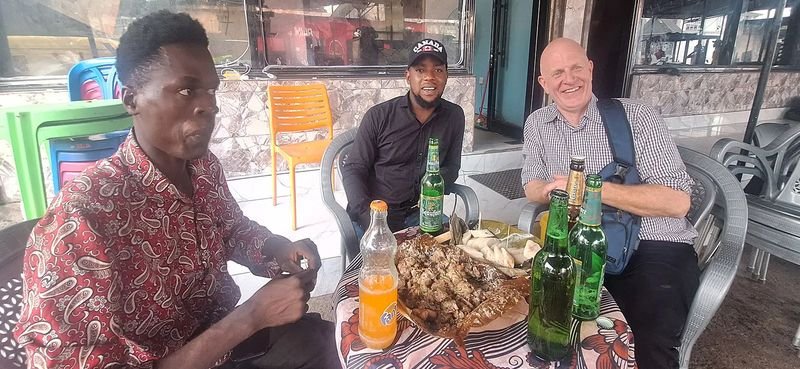 Sharing grilled fish and drinks at a street restaurant in the Congo
