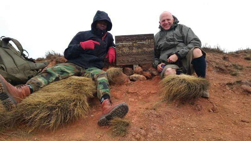 Resting at the summit marker of Mount Cameroon