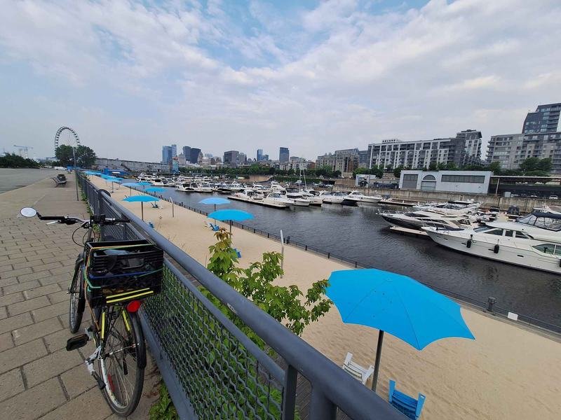 Blue umbrellas on Clock Tower Beach in the Old Port, with the marina and the Ferris wheel